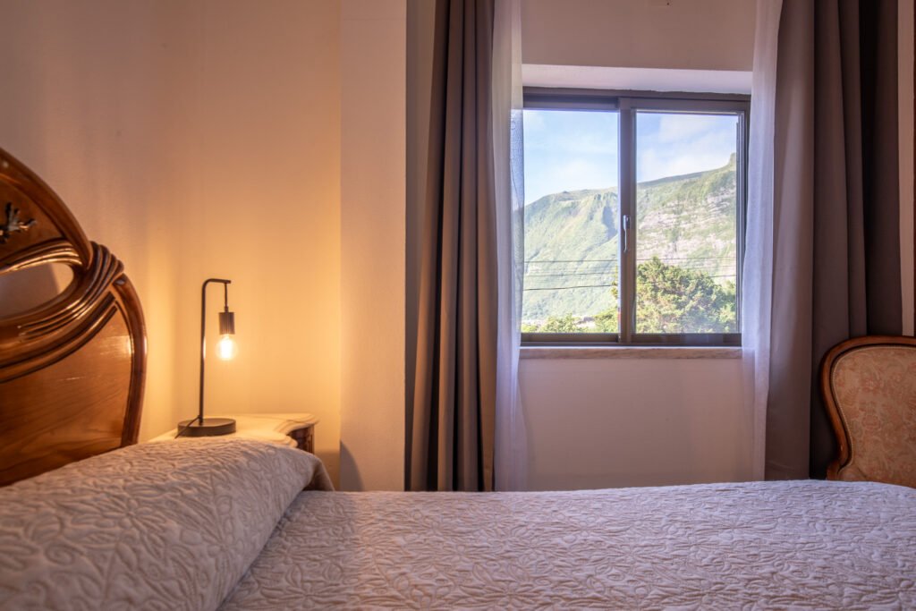 small bedroom with mountain and waterfall view at Casa da Sogra in Fajã Grande, featuring a comfortable double bed