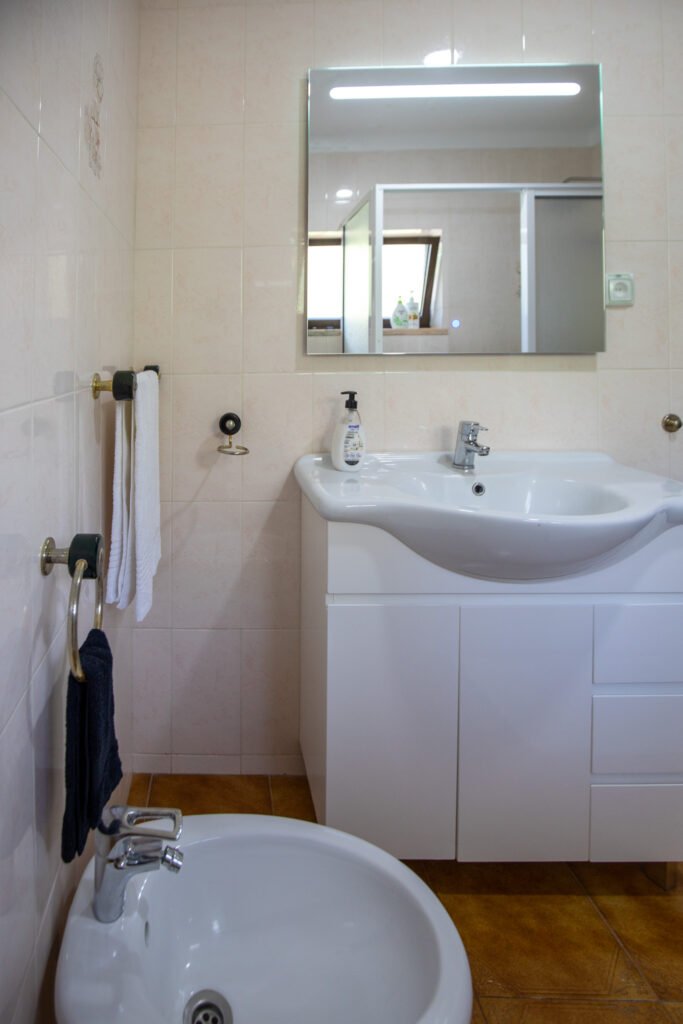 Bathroom at Casa da Sogra in Fajã Grande with bathtub, bidet, lighted mirror, toiletries, and fresh towels.